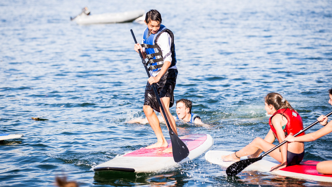 Boy does stand up paddleboarding at summer camp