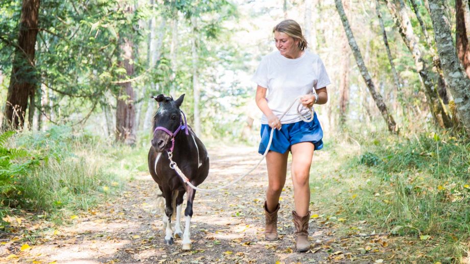 Camper walks pony through woods