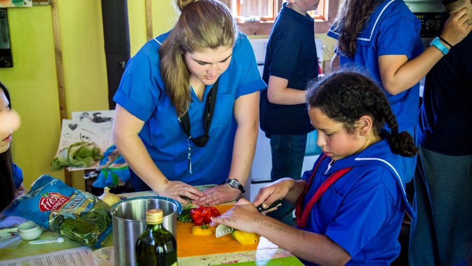 Counselor helps camper cut vegetables