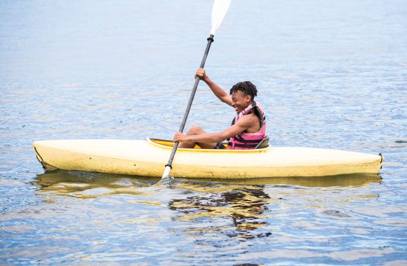 Boy kayaks at summer camp